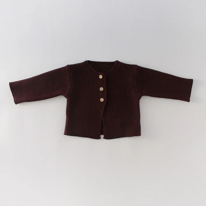 Dark brown knitted baby cardigan with three wooden buttons on a light background