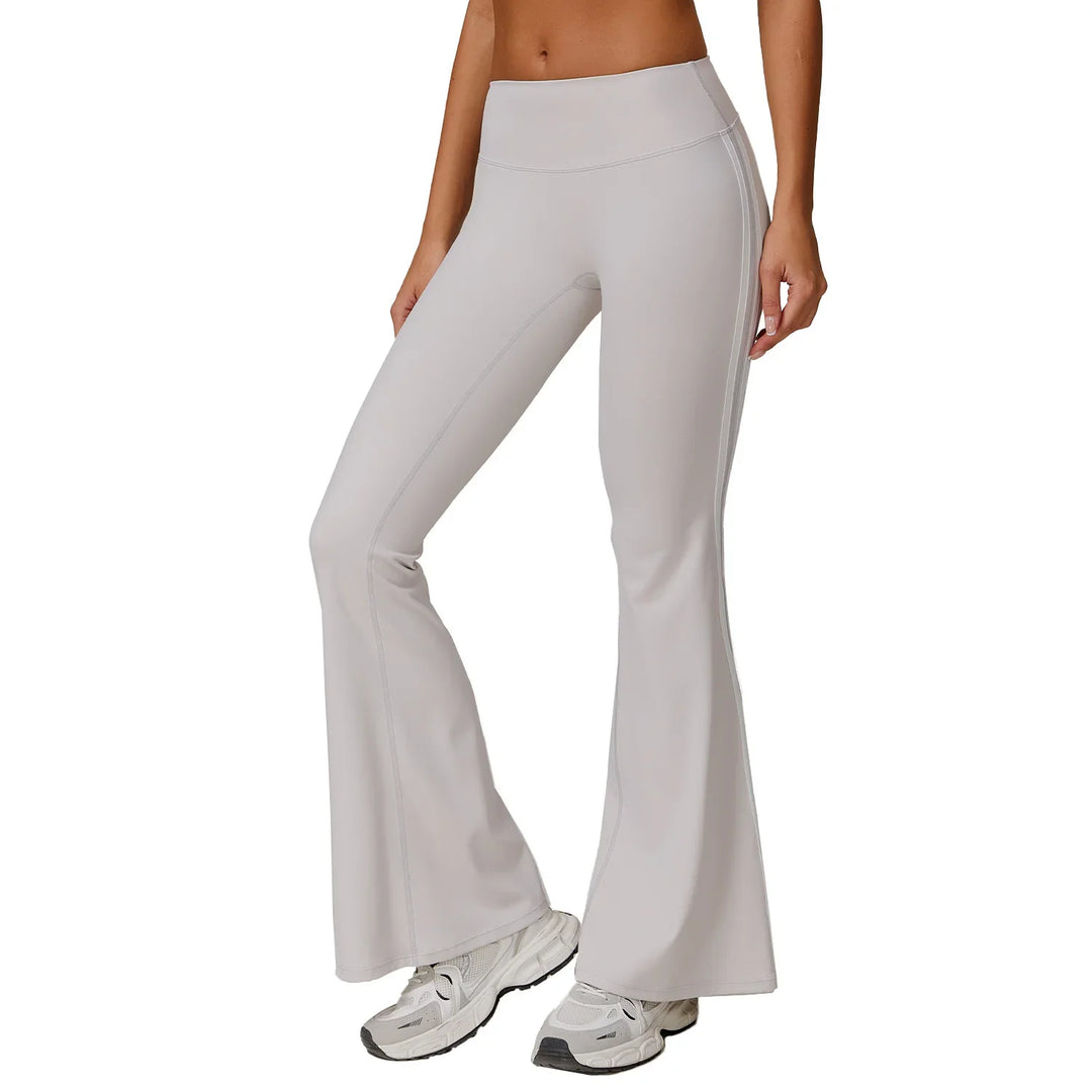 woman wearing light gray flared yoga pants and white athletic sneakers on white background