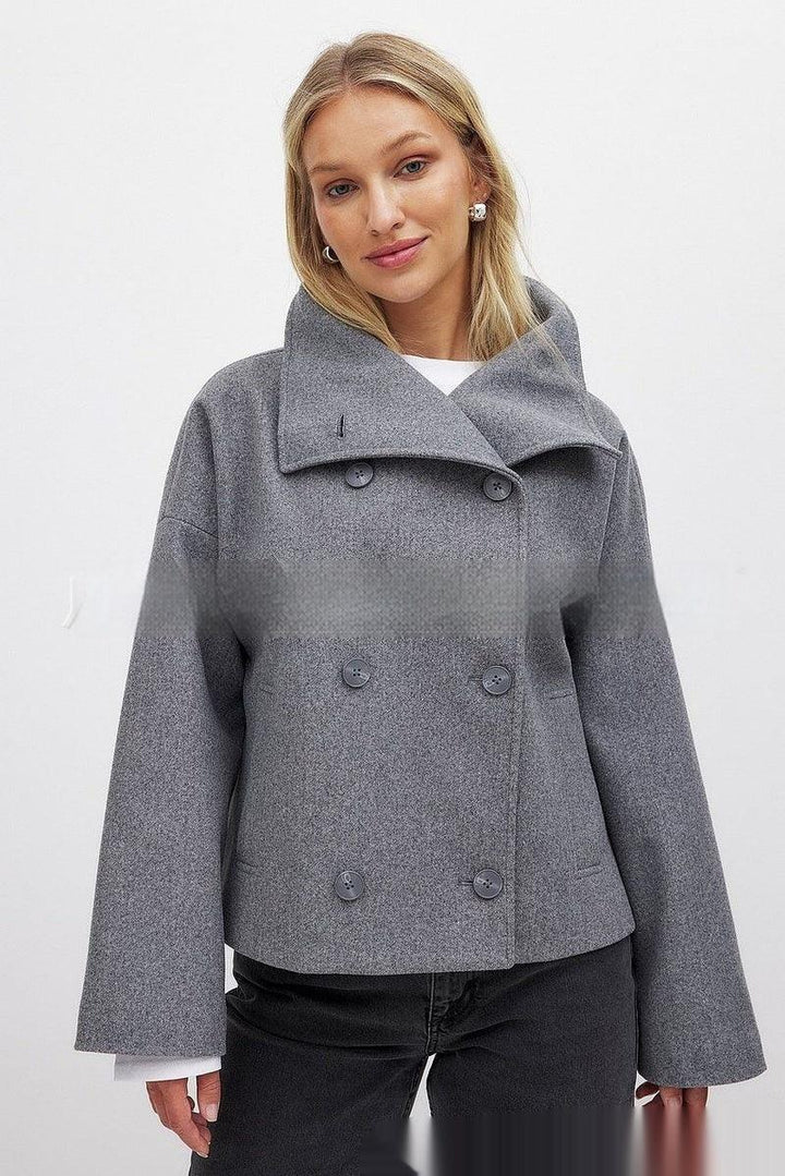 Woman wearing a grey double-breasted wool coat with wide collar and black pants