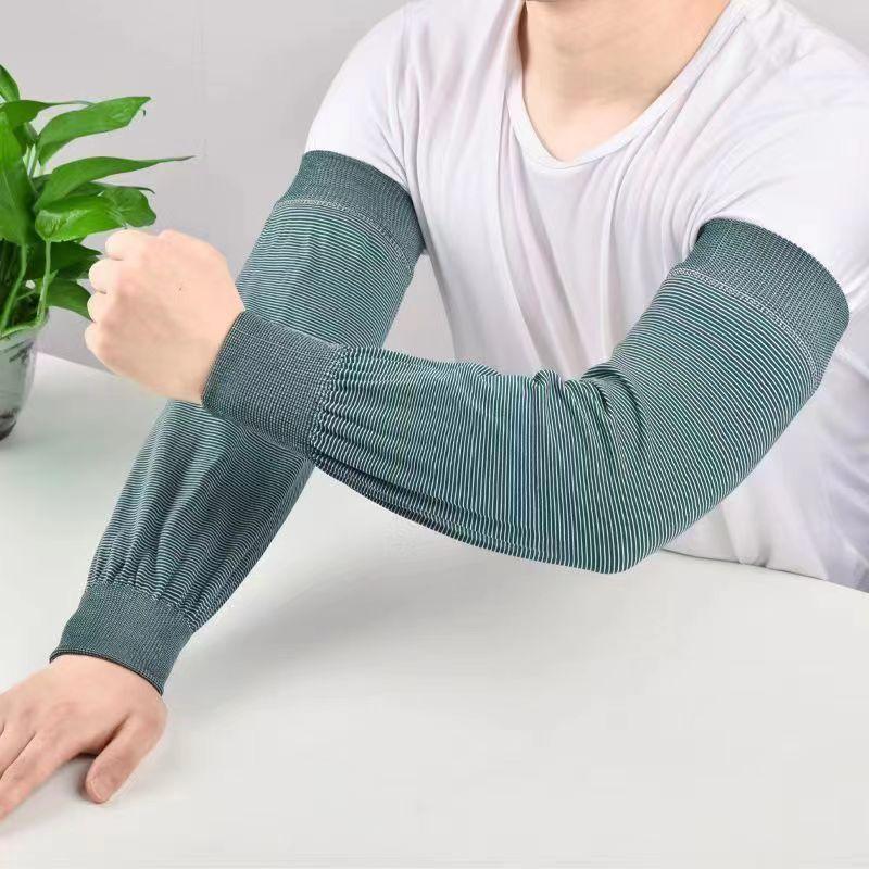 Person wearing striped arm sleeves in green and white sitting at a white table with a green plant nearby