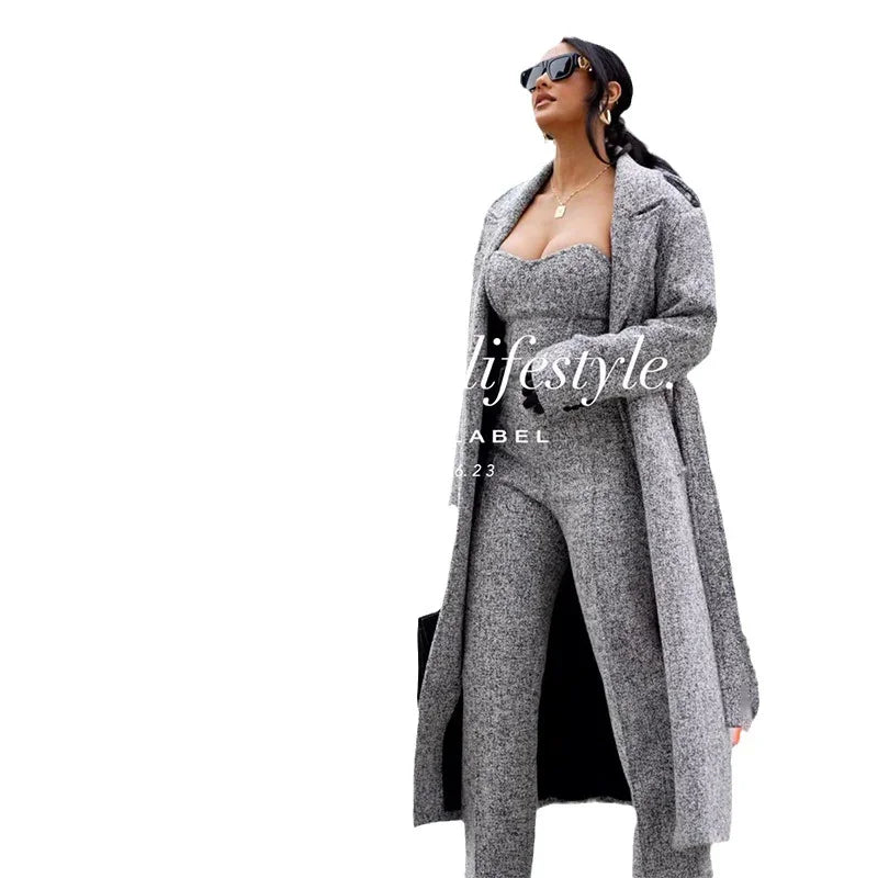 Stylish woman wearing grey tweed coat and matching strapless jumpsuit with sunglasses on white background