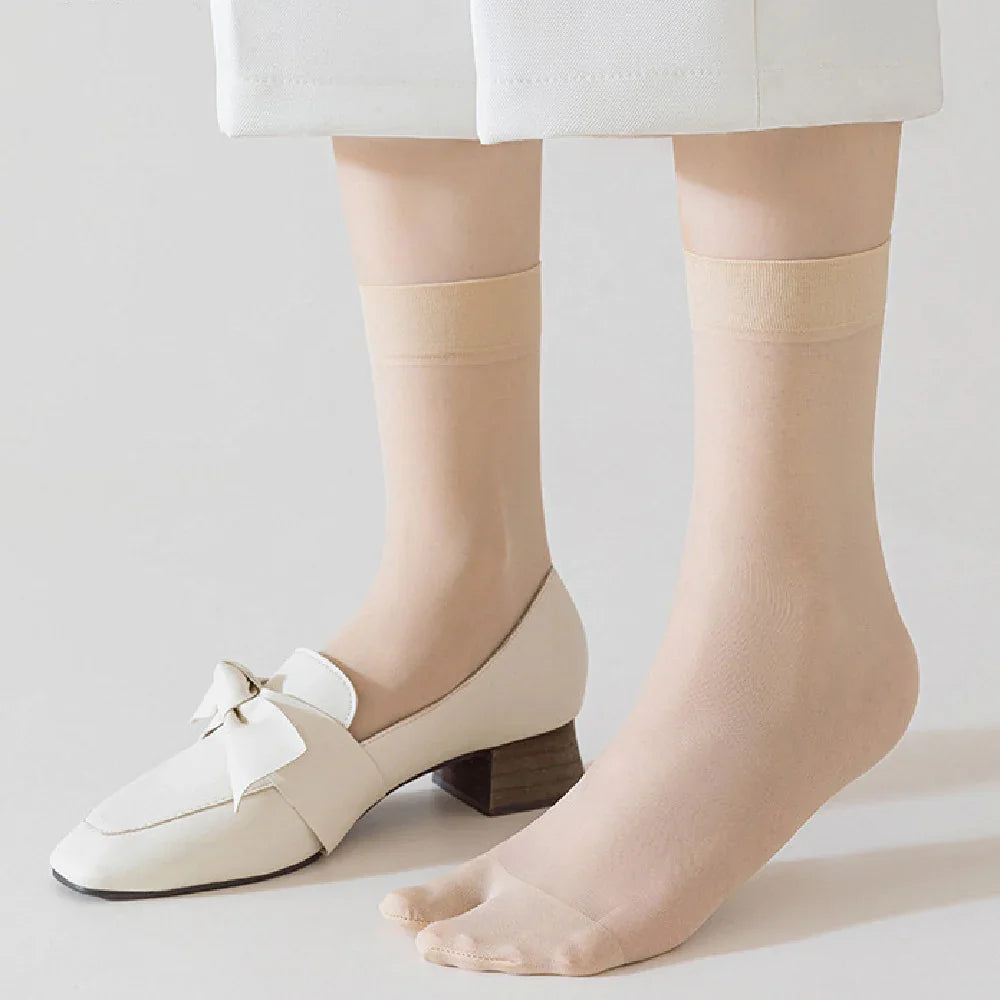 Close-up of feet wearing nude sheer ankle socks with white leather shoes featuring a bow detail