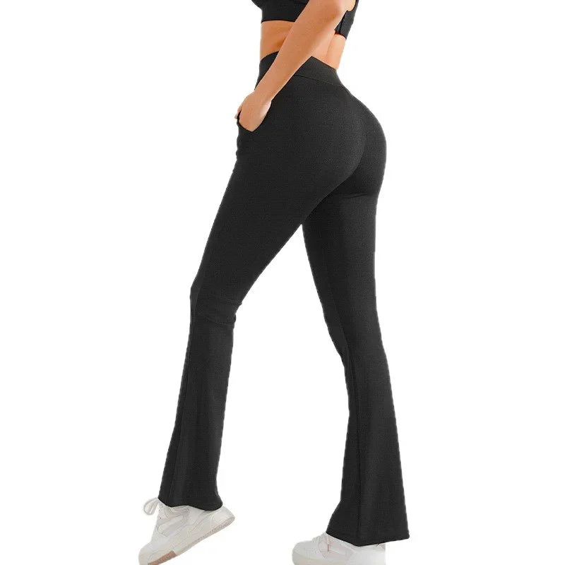 Woman wearing black high-waisted flare leggings and white sneakers on white background
