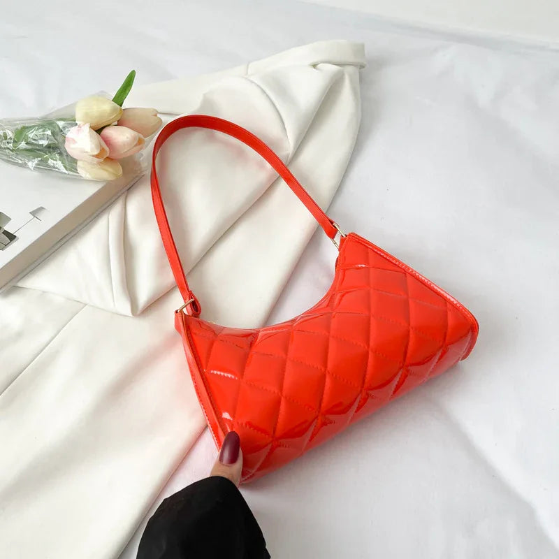 Glossy red quilted shoulder bag on white fabric with tulip flowers and book