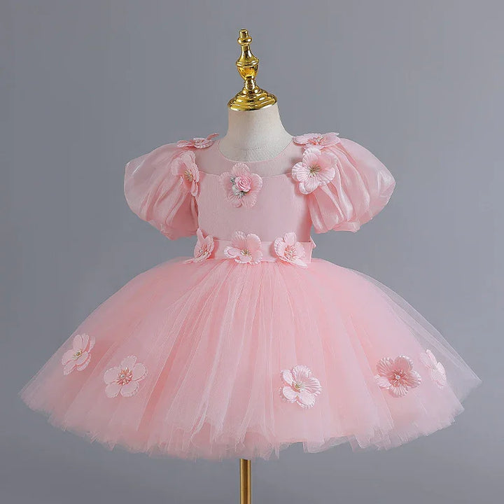 Pink toddler dress with puff sleeves and floral applique on tulle skirt, displayed on mannequin