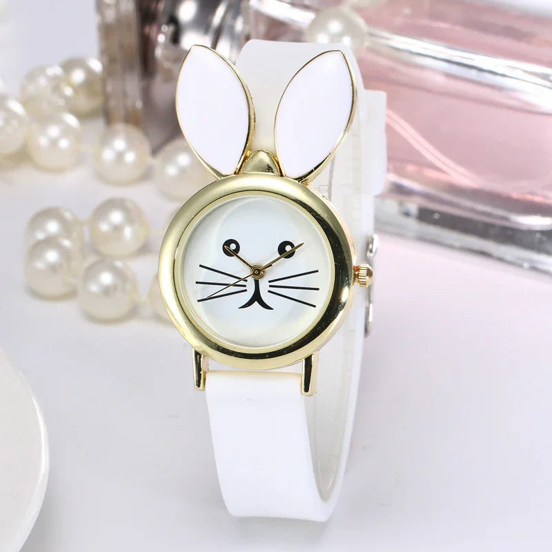 White wristwatch with gold bunny ears and rabbit face design, white strap, pearls background