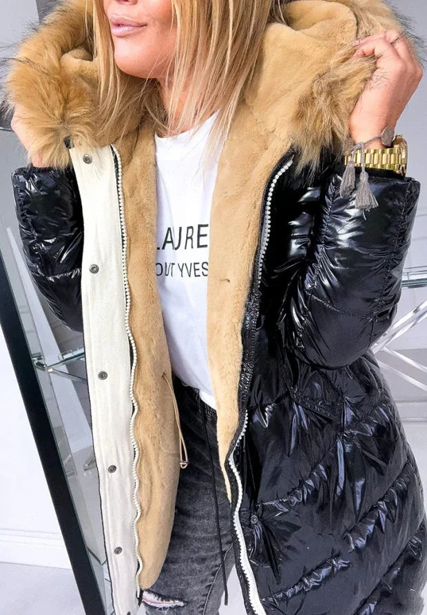 Woman wearing black shiny puffer jacket with beige fur lining and hood, paired with white graphic tee and ripped jeans