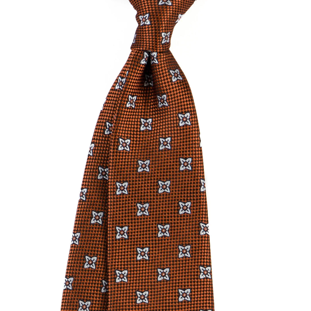 Orange patterned men’s silk tie with white and black flower motifs on checkered background