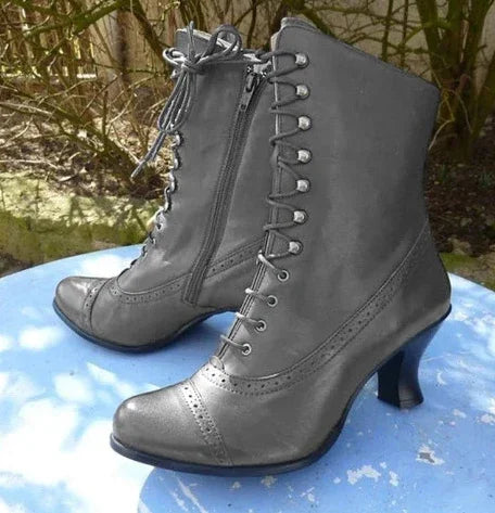 Pair of black vintage lace-up ankle boots with side zipper and block heels on blue surface