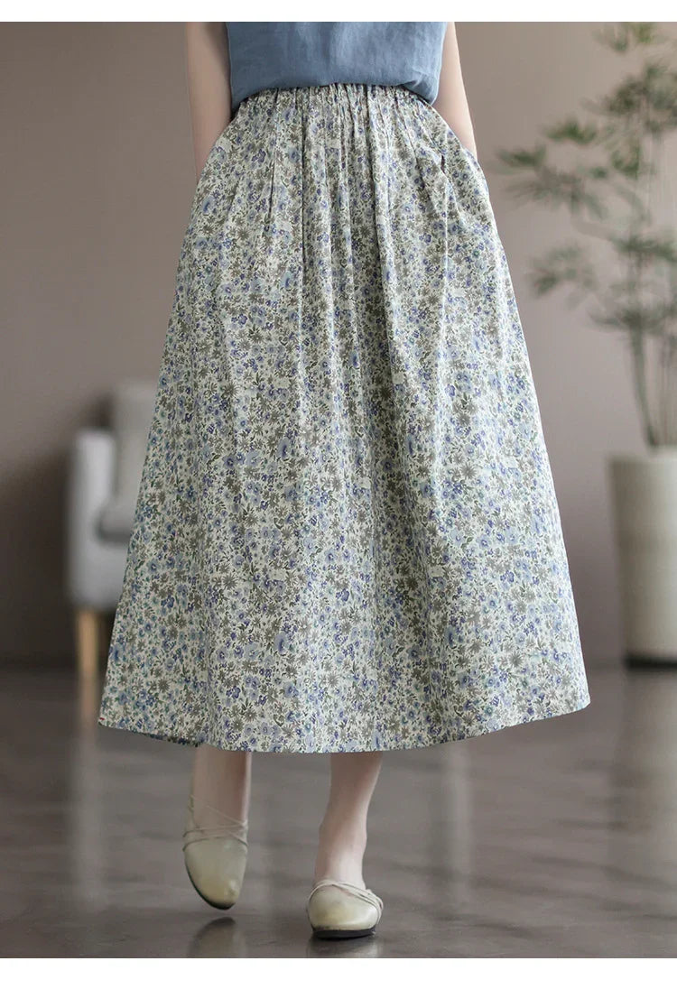 Woman wearing a floral midi skirt with blue and green flowers and beige ballet flats on a polished floor