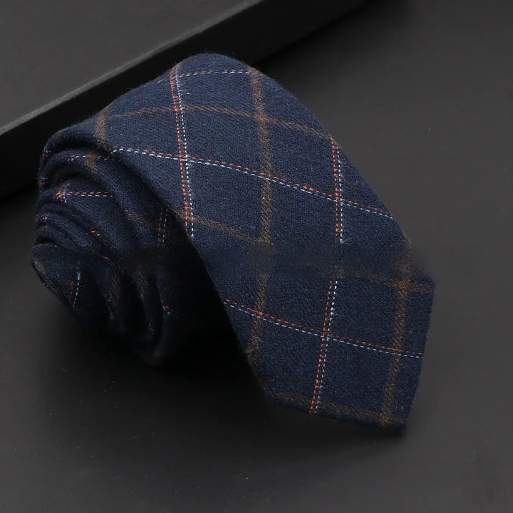 Rolled navy blue wool tie with brown and light blue windowpane check pattern on black background