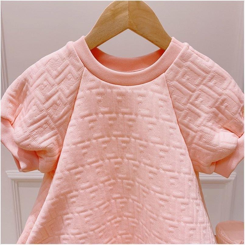 Soft pink textured baby dress with puff sleeves hanging on wooden hanger