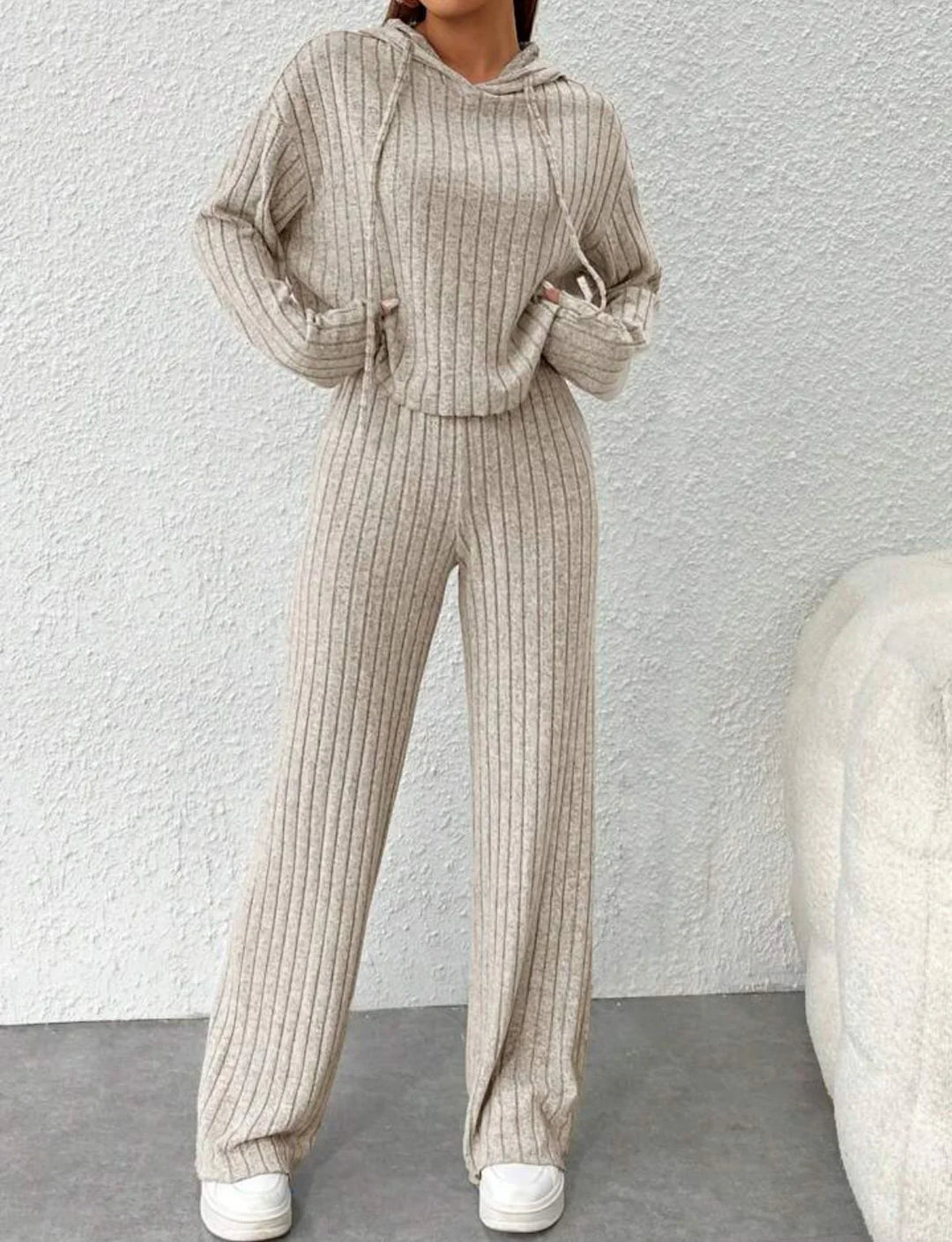 Woman wearing beige ribbed knit hoodie and matching wide-leg pants with white sneakers indoors