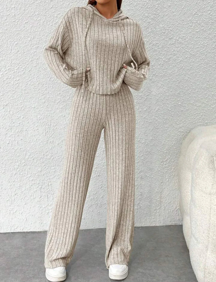 Woman wearing beige ribbed knit hoodie and matching wide-leg pants with white sneakers indoors