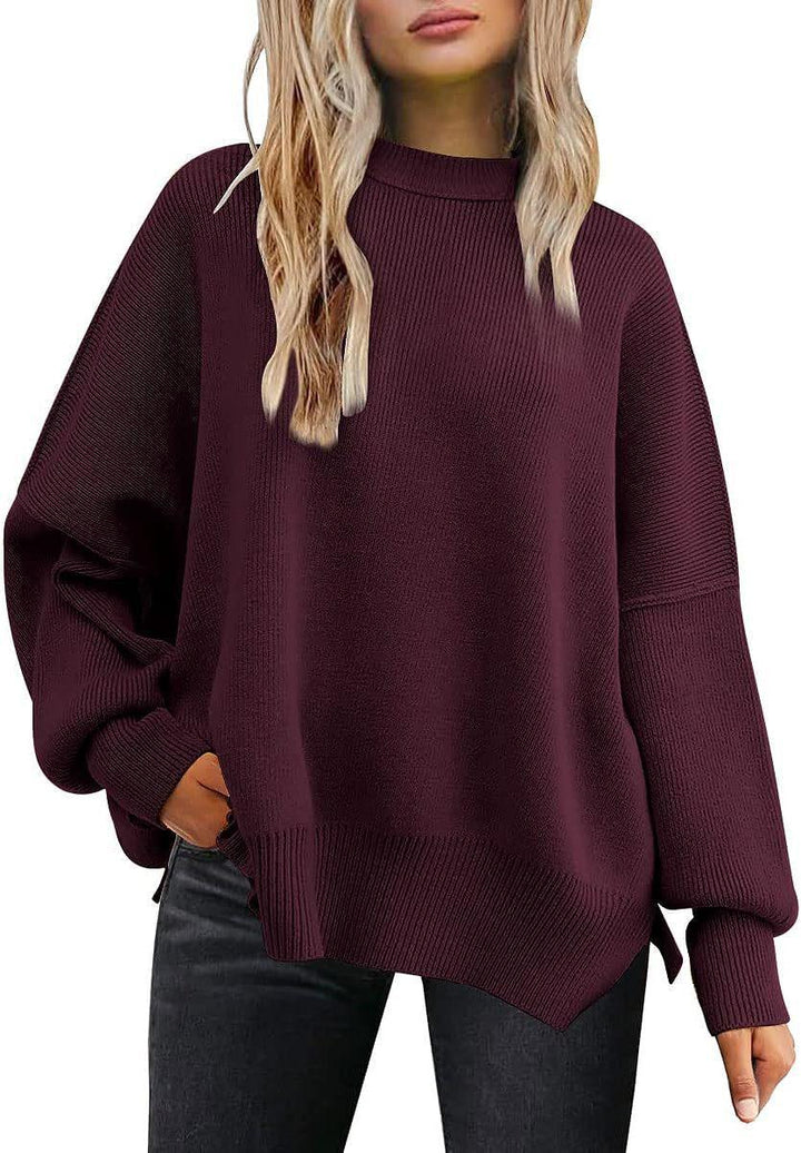 Woman wearing oversized dark purple knit sweater with ribbed hem and cuffs, paired with black jeans