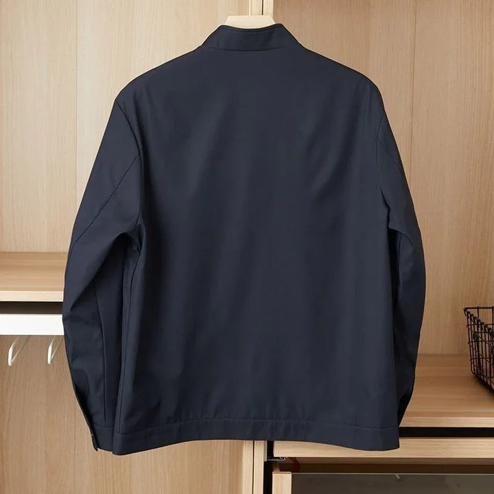 Back view of a navy blue casual jacket hanging on wooden wardrobe