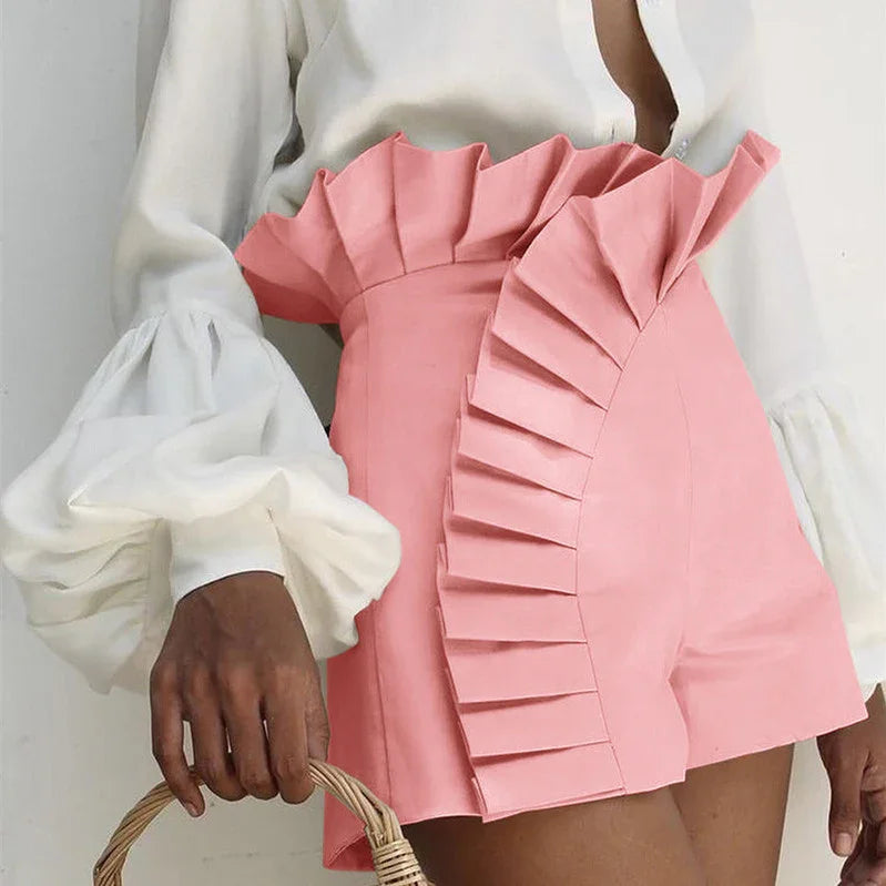 Woman wearing pink high-waisted shorts with pleated ruffle detail and white puff sleeve blouse holding wicker basket