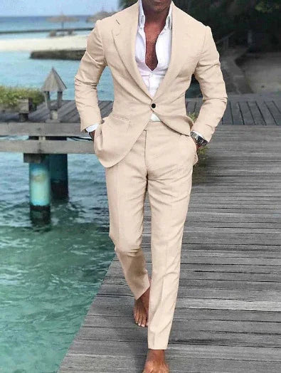 Man wearing a beige suit with white shirt, barefoot, walking on wooden dock over turquoise water
