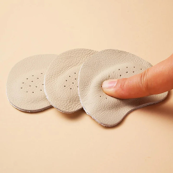 Beige leather gel heel pads with ventilation holes, finger pressing soft cushion