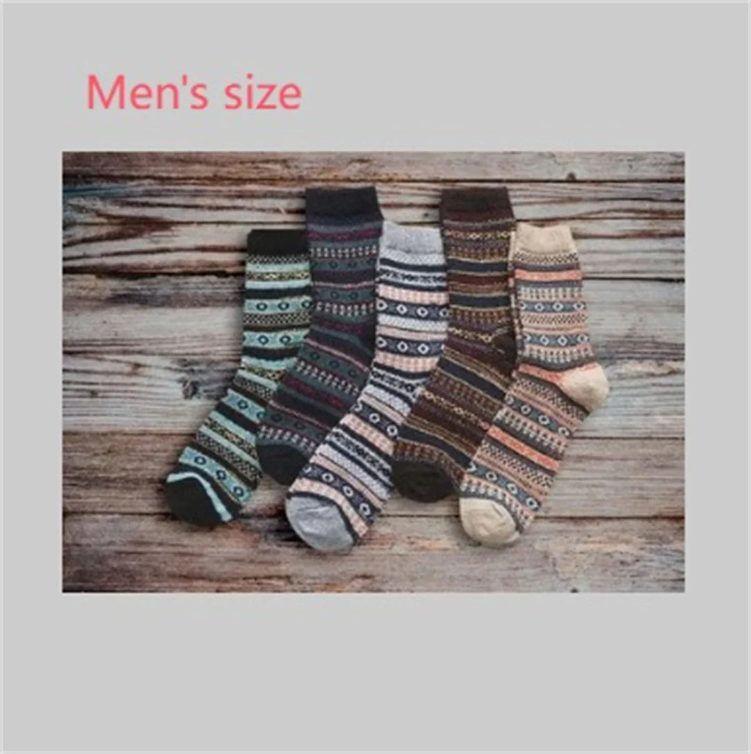 Five pairs of men's size patterned wool socks in various colors on rustic wooden background