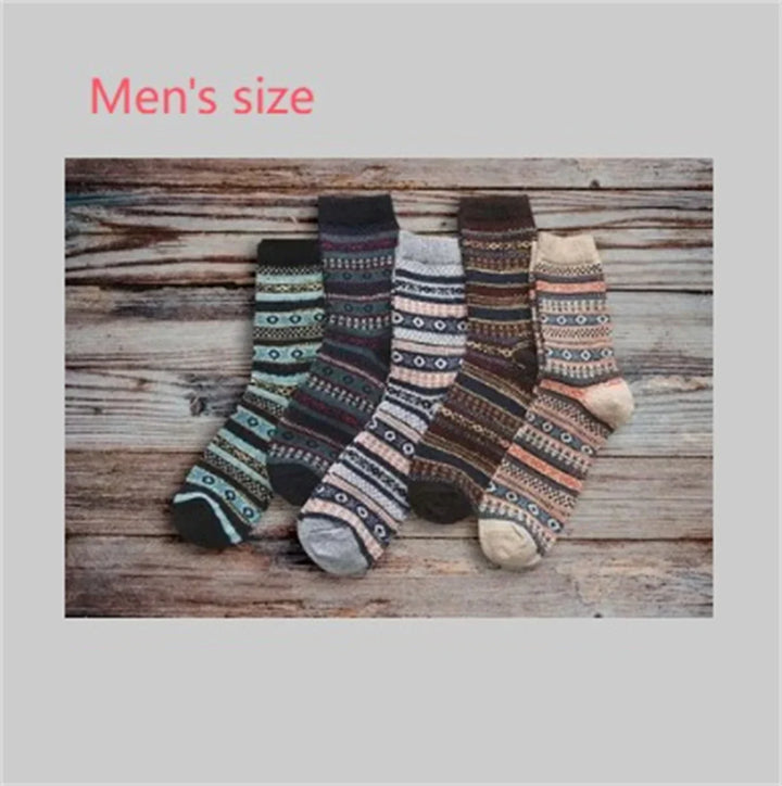 Five pairs of men's size patterned wool socks in various colors on rustic wooden background