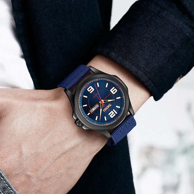 Men's wristwatch with blue dial, large numerals, red second hand, and blue fabric strap on wrist