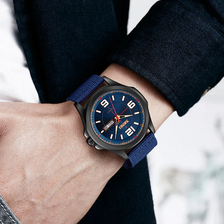 Men's wristwatch with blue dial, large numerals, red second hand, and blue fabric strap on wrist