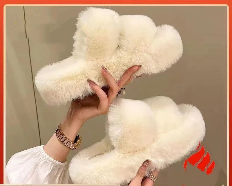 Hand holding a pair of white fluffy faux fur slippers with a beige background