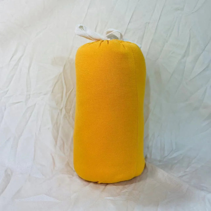 Bright yellow fabric draft stopper with white tie on wrinkled white cloth background