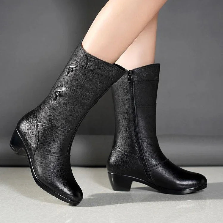 Close-up of black mid-calf leather boots with small heel and decorative buttons on side