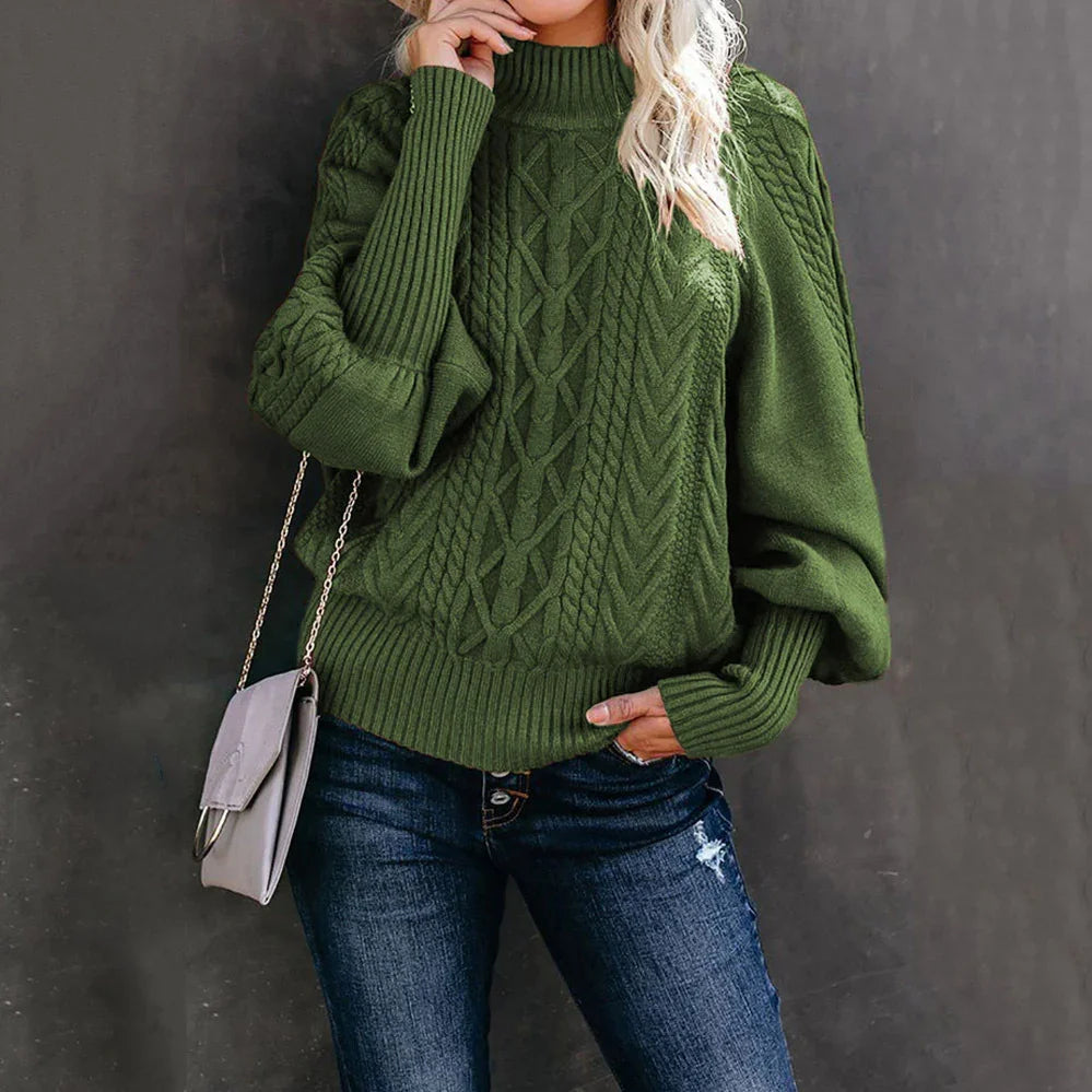 Woman wearing green cable knit sweater with balloon sleeves and dark blue distressed jeans