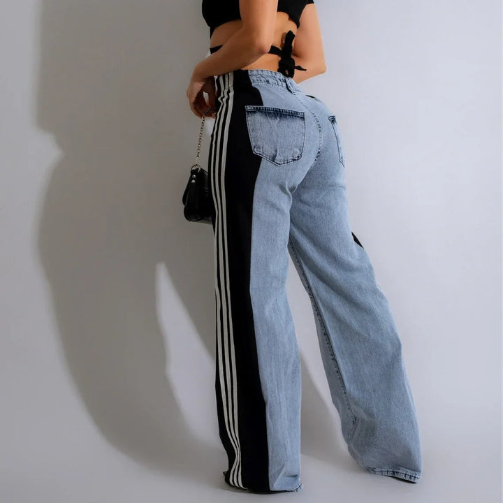 Woman wearing light blue denim jeans with black side panels and white stripes, paired with a black crop top