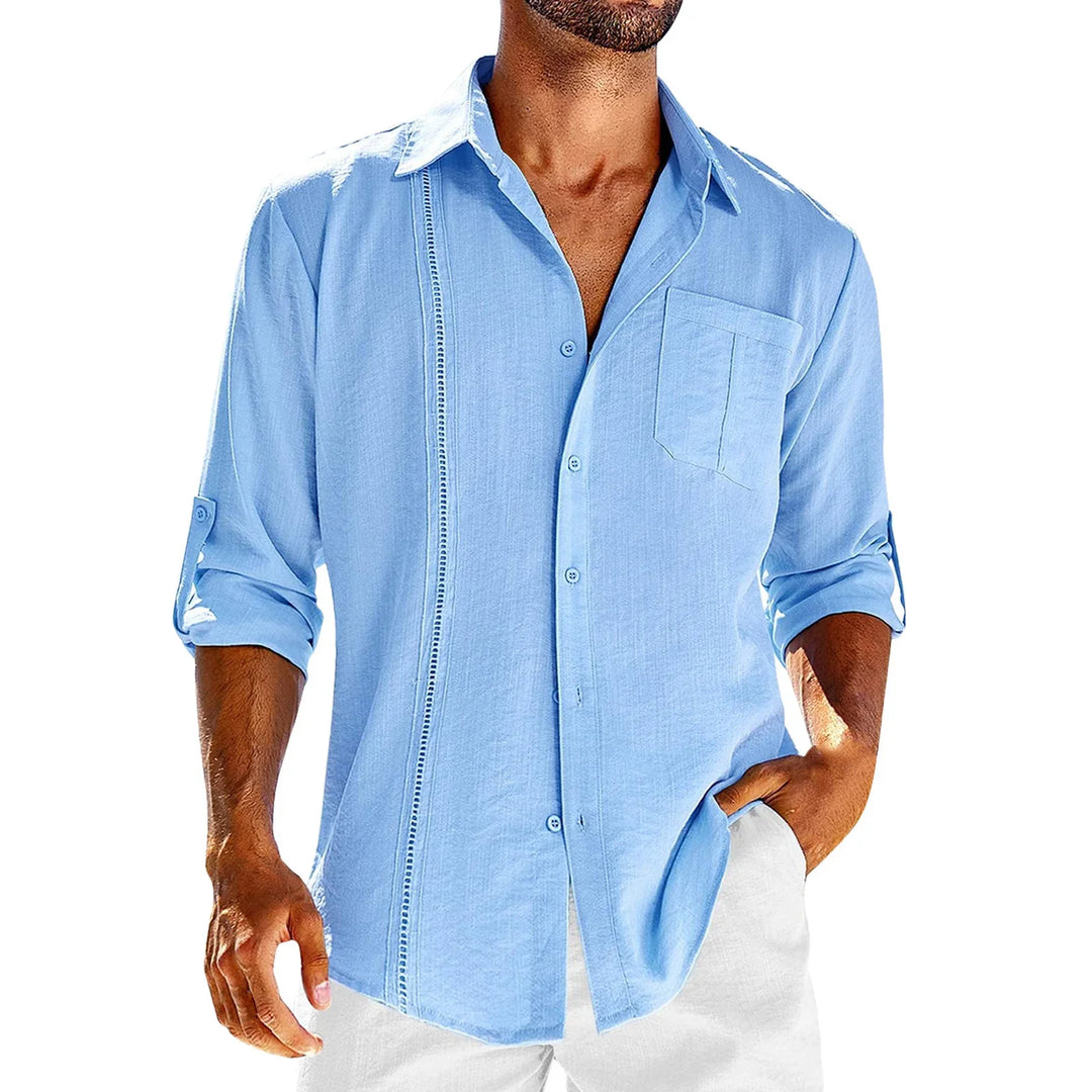 Man wearing light blue casual button-up shirt with rolled sleeves and white pants