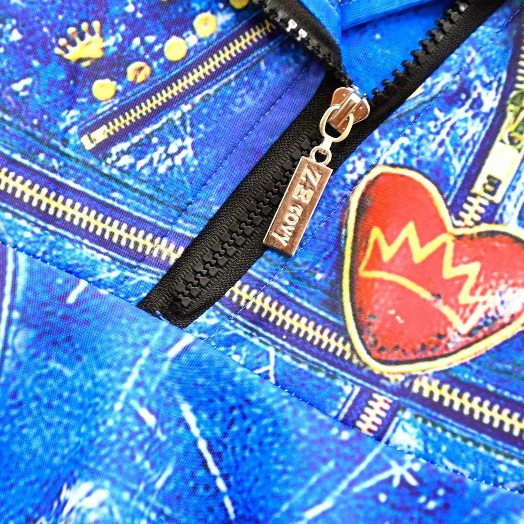 Close-up of blue denim fabric with gold zippers, red heart patch, and metal zipper pull with ZAZOWY logo
