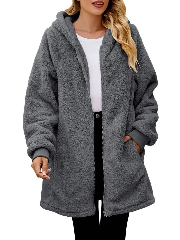 Woman wearing oversized grey fuzzy hooded zip-up jacket with pockets