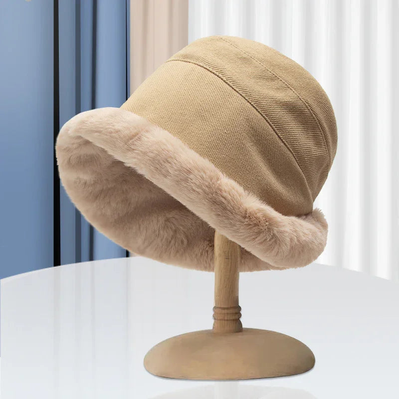 Beige winter bucket hat with soft faux fur trim displayed on wooden stand