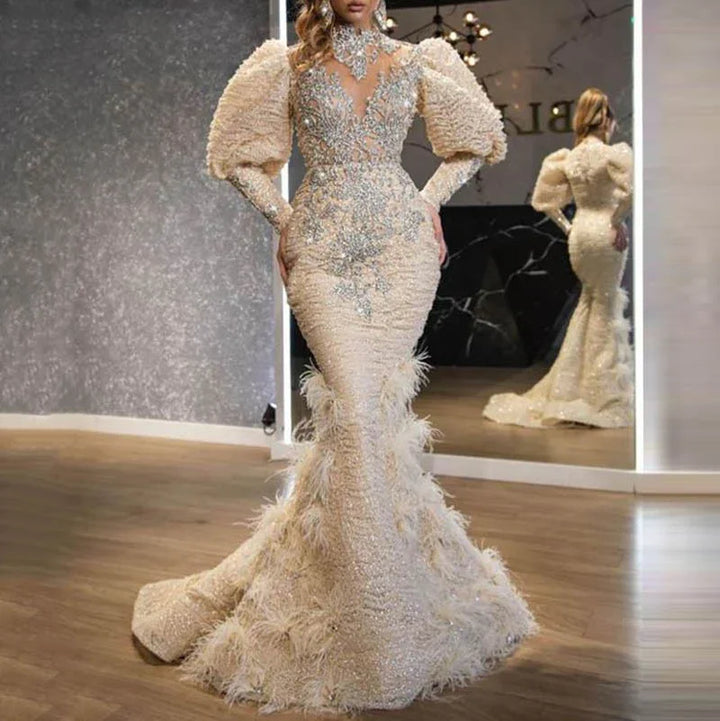 Elegant beige mermaid gown with puffed sleeves, intricate silver embellishments, and feather details