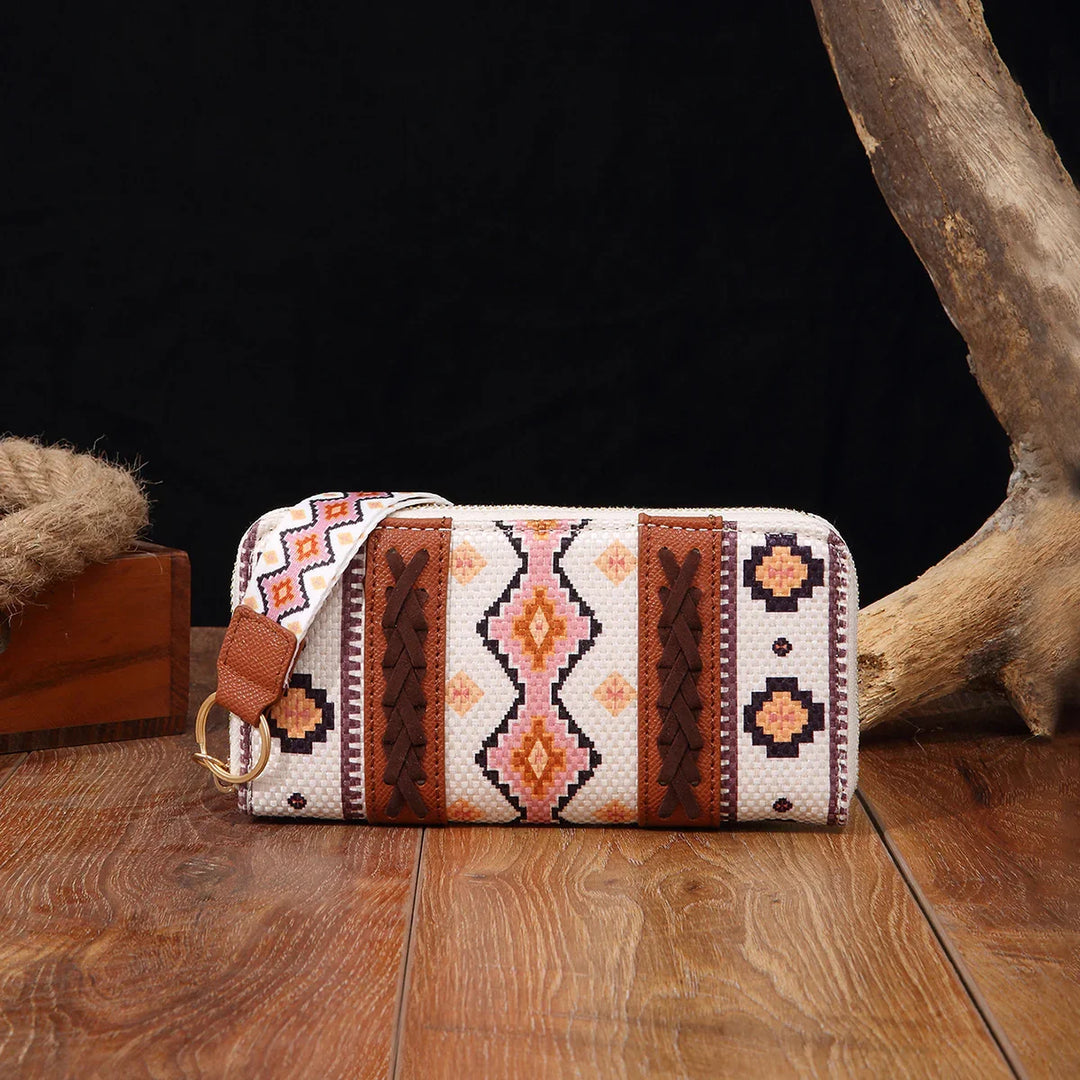 Boho style woven clutch bag with geometric pink and brown patterns on wooden surface
