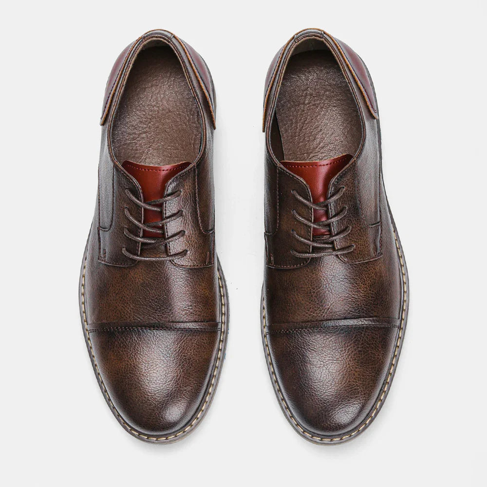 Pair of brown leather men's dress shoes with laces and textured finish on white background