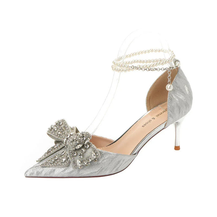 Elegant silver low heel shoe with embellished bow and pearl ankle straps