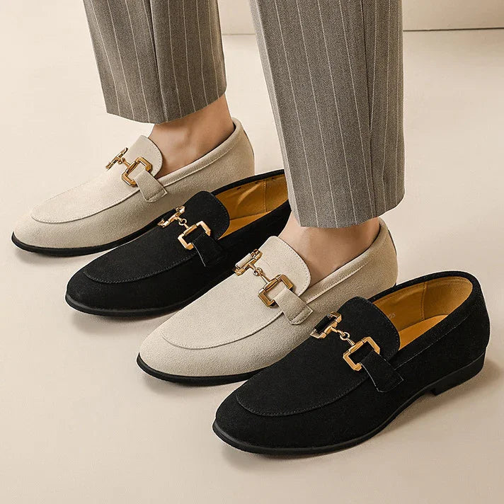Men's suede loafers in beige and black with gold horsebit detailing, worn with pinstripe pants