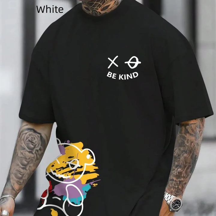 Black t-shirt with white text 'BE KIND' and abstract teddy bear graphic, worn by tattooed person