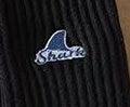 Close-up of black ribbed fabric with a small embroidered blue and white shark logo