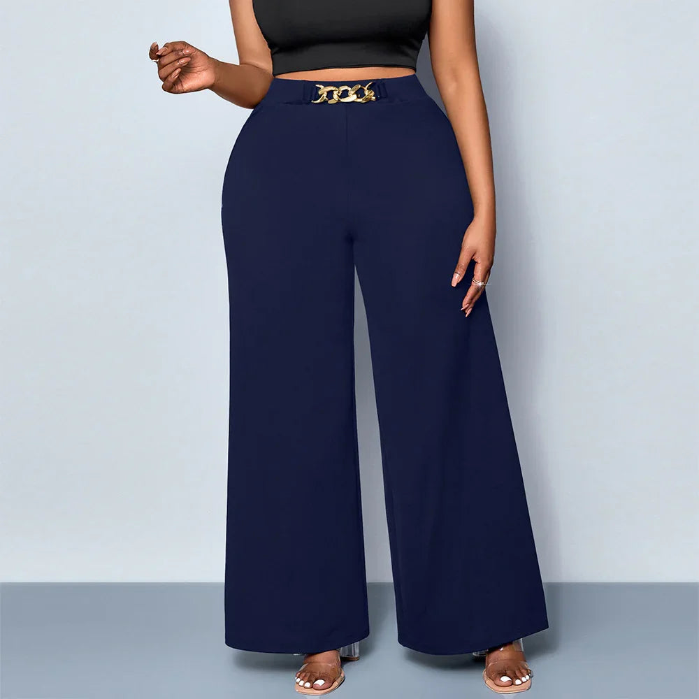 Woman wearing navy blue high waist wide-leg pants with gold chain detail and black crop top