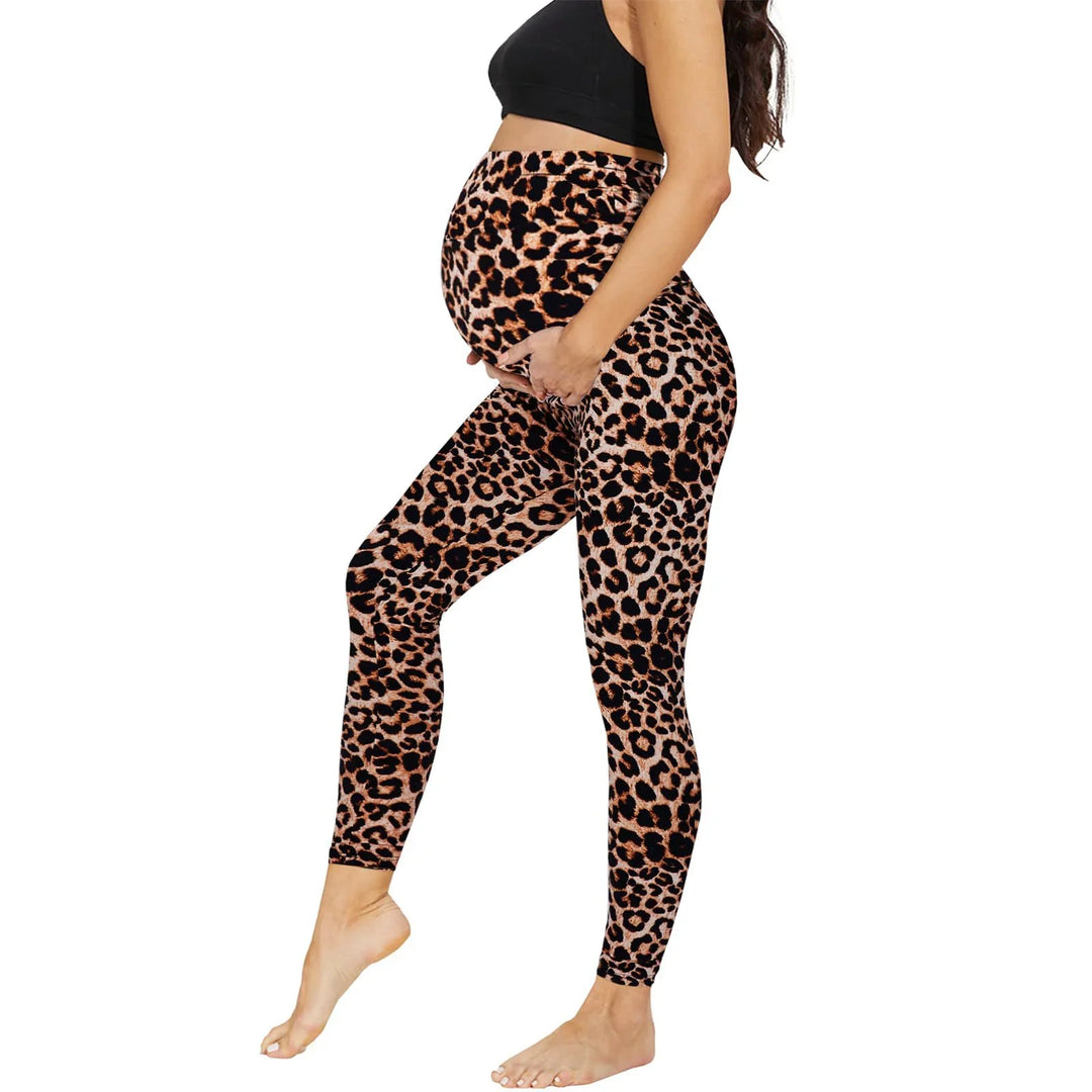 Pregnant woman wearing leopard print maternity leggings and black crop top on white background