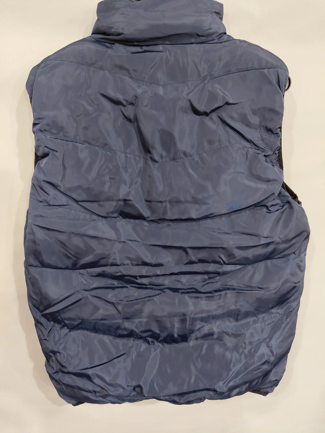 back view of navy blue padded sleeveless winter vest with quilted stitching