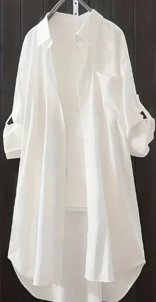 White long-sleeve button-up shirt dress with rolled cuffs, hanging on hanger against dark background