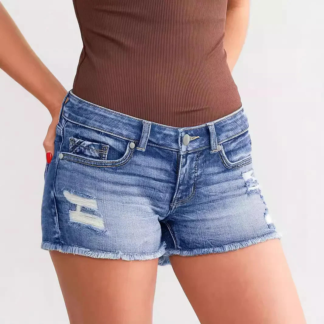 Woman wearing distressed blue denim shorts with frayed hems and a brown ribbed top