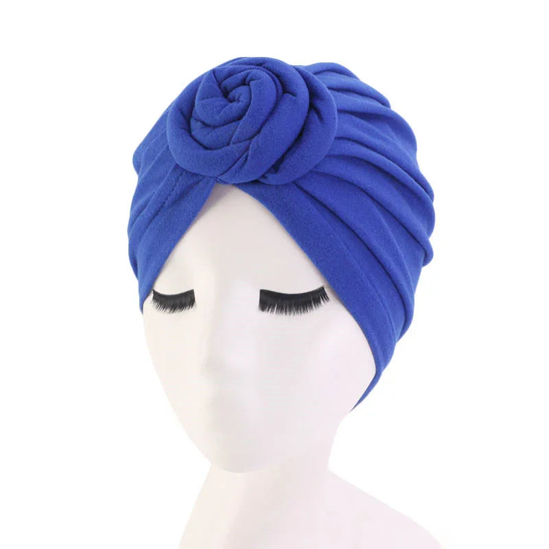 Blue turban headwrap with rose detail on white mannequin head with long eyelashes