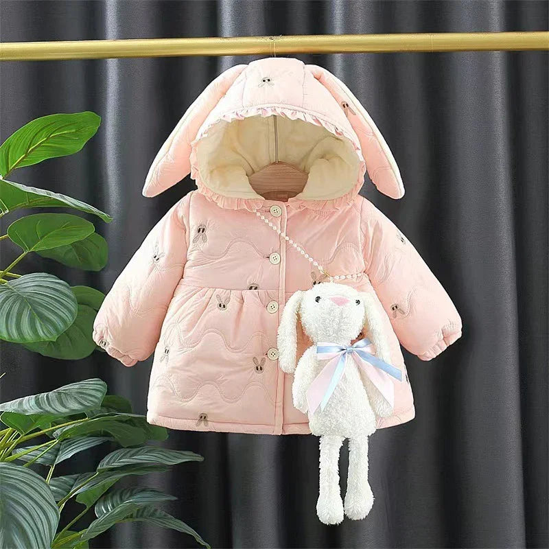 Pink baby jacket with bunny ear hood and matching plush bunny bag hanging on a golden rack